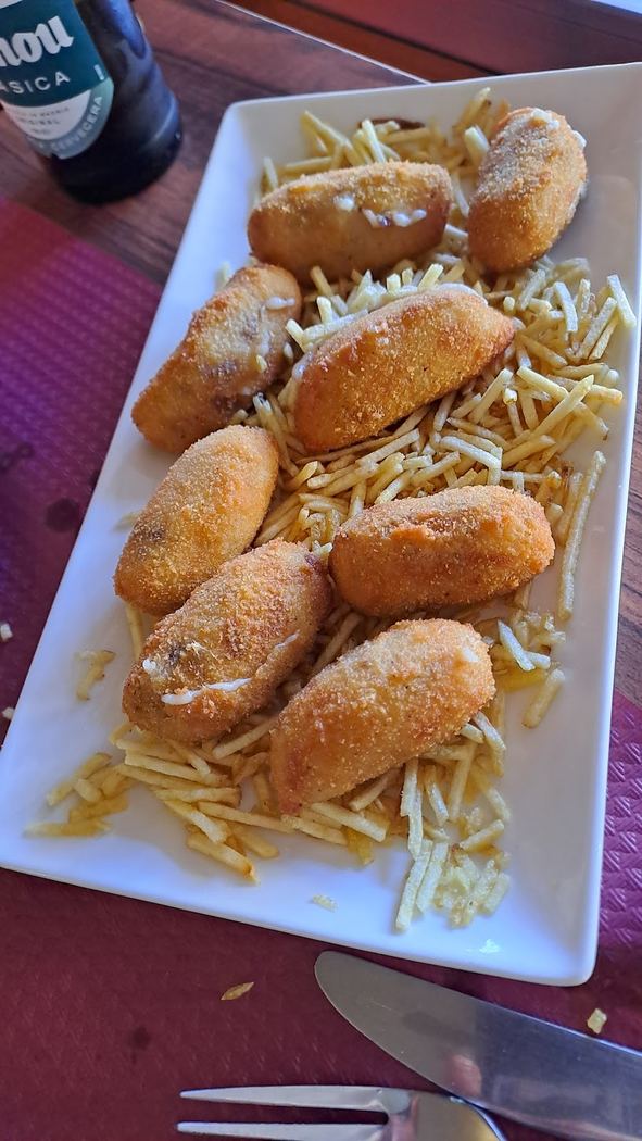 Croquetas caseras variadas servidas sobre un lecho de patatas paja